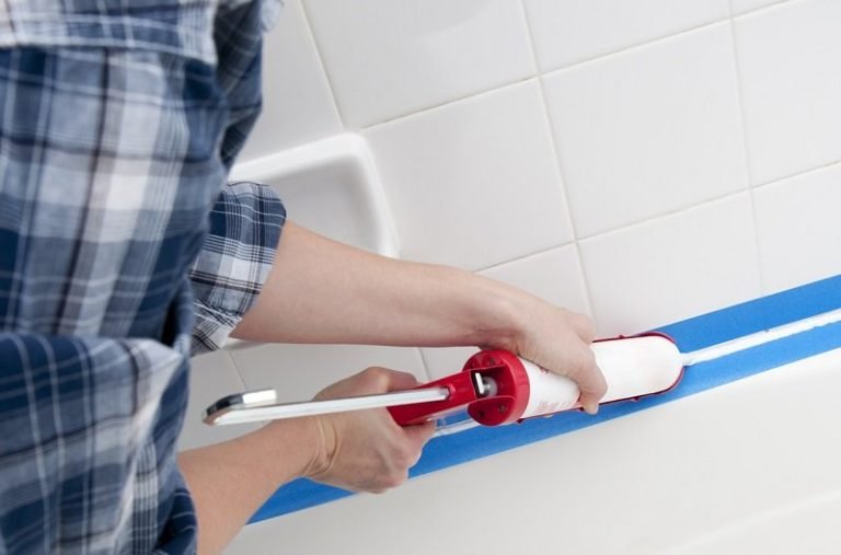 Applying fresh caulk along a tub and tile joint
