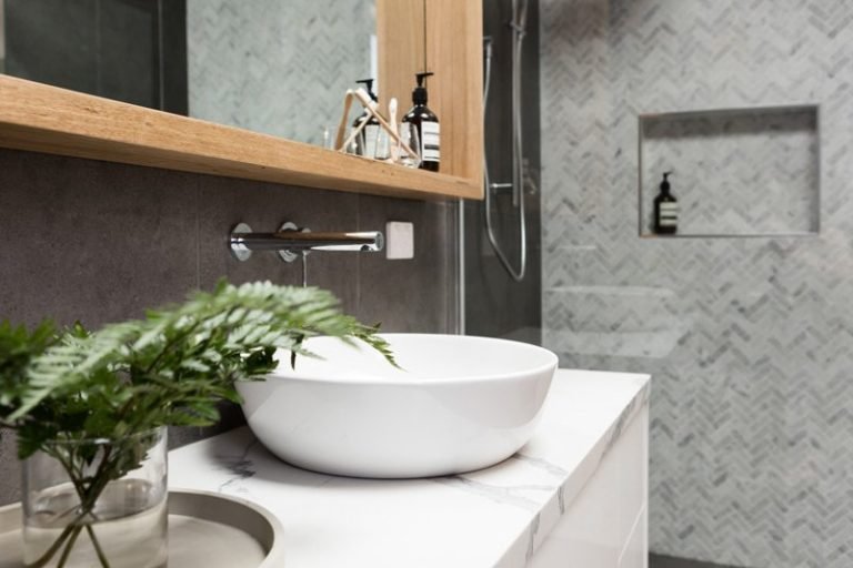 Modern bathroom vanity with a vessel sink and herringbone tile wall